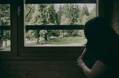 Side view of woman looking through window