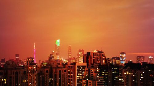 Illuminated buildings in city against sky at night