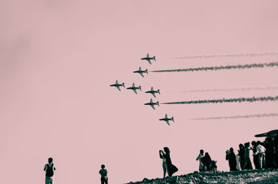 Group of people at airplane against sky