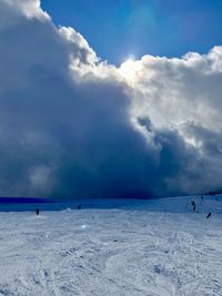 People on snow covered land against sky