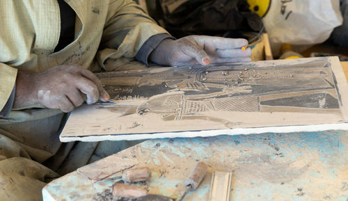 Closeup view of unrecognizable and clopped arab artisan man working in hand made stone engraving 