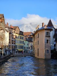Scenic view of old town/city traverse by river with snowy mountains behind