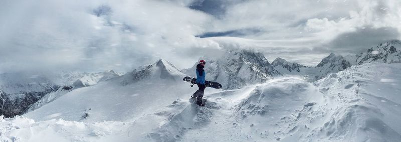 Side view of man walking on snowcapped mountains against sky