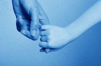 Cropped image of child holding mother finger