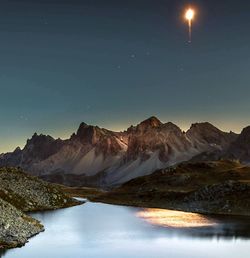 Scenic view of lake and mountains against sky at night