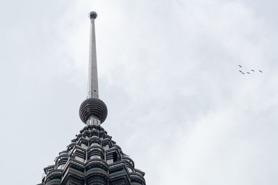 Low angle view of communications tower against cloudy sky