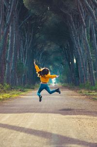 Rear view of woman jumping on road