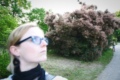 Portrait of woman standing on tree trunk