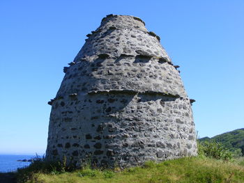 Low angle view of old ruin against clear blue sky on sunny day