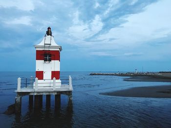 Lighthouse by sea against sky