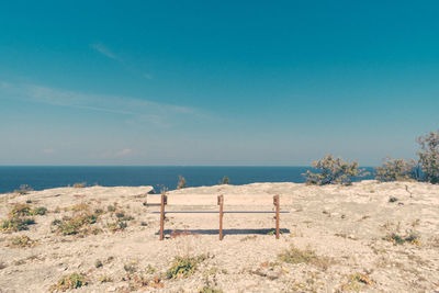Empty bench on cliff with sea in background