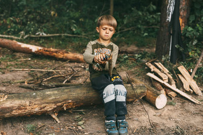 A boy-child makes a fire from wood branches in a forest camping. camping in the forest in summer. 