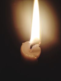 Close-up of lit candle in darkroom