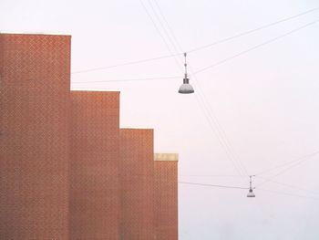 Low angle view of lamps by building against sky