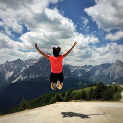 Full length of man jumping on mountain against sky