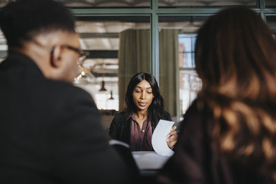 Female entrepreneur reviewing document in business meeting at office