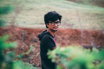 Young man looking away while standing on land