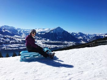 Man skiing on snowcapped mountain against blue sky