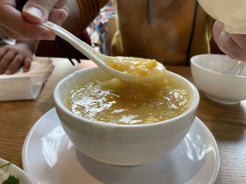 Close-up of hand holding ice cream in bowl on table