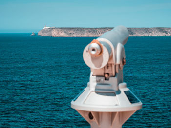 Coin-operated binoculars by sea against clear sky