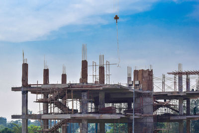 Cranes at construction site against sky in city