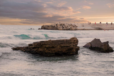 Rocks on beach against sky during sunset