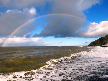 Scenic view of sea against rainbow in sky