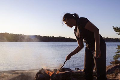 Woman at camp fire, lake on background