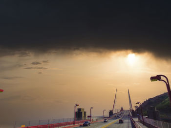 Cars on street against sky during sunset