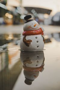 Close-up of snowman figurine on puddle