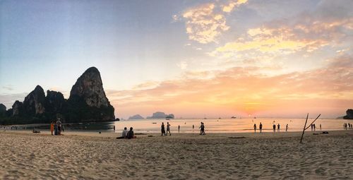 People on beach against sky during sunset