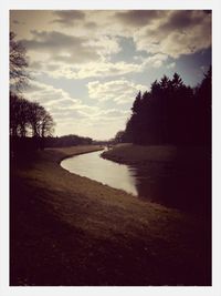 Scenic view of river against cloudy sky