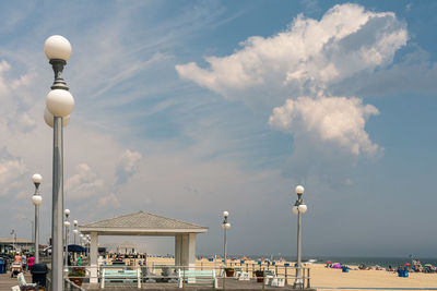 People on beach by street against sky