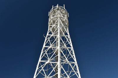 Low angle view of communications tower against clear blue sky