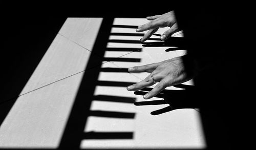 Optical illusion of cropped hands playing piano on floor