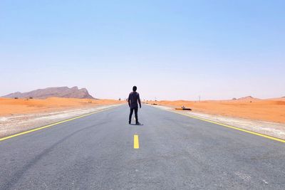 Rear view of man walking on road