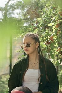 Young woman wearing sunglasses while standing against trees