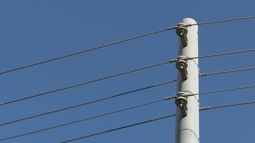 Power lines against clear blue sky