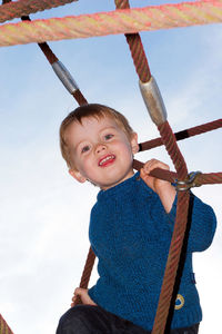 Low angle portrait of smiling boy against sky