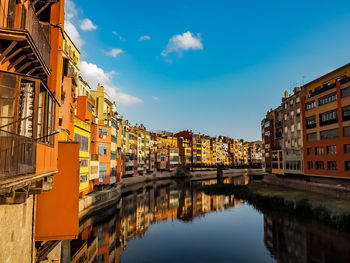 Reflection of buildings in canal against sky