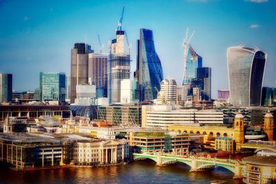 Modern buildings by river against sky in city