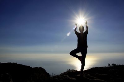 Silhouette woman standing on street against sky during sunset