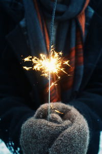 Midsection of woman holding lit sparkler