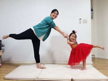 Portrait of cheerful mother and daughter practicing yoga at home