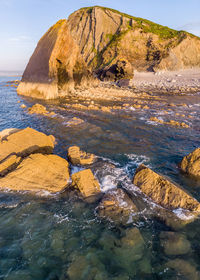 Rocks on shore by sea against sky