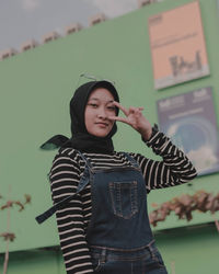 Low angle view portrait of teenage girl standing against built structure