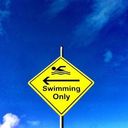 Low angle view of sign board against blue sky