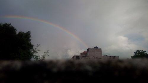 Low angle view of rainbow over buildings against sky