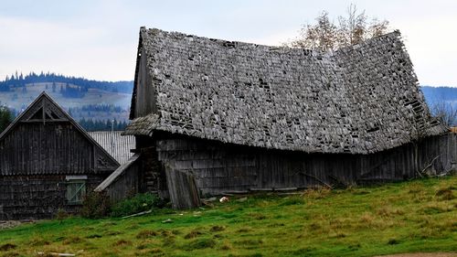 Old abandoned house on field against sky