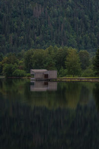 Scenic view of lake and sauna by trees in forest